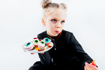 Image showing Little girl witch in black dress over magical accessories. Halloween, the studio evening.