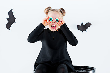 Image showing Little girl witch in black dress over magical accessories. Halloween, the studio evening.