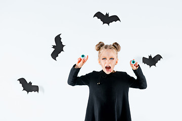 Image showing Little girl witch in black dress over magical accessories. Halloween, the studio evening.