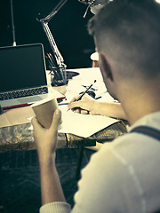 Image showing Vintage hipster wooden desktop side view, male hands with cup and holding a pencil