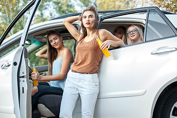 Image showing The young women in the car smiling and drinking juice