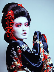 Image showing young pretty geisha in kimono with sakura and red decoration des