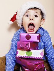 Image showing little cute boy with Christmas gifts at home. close up emotional