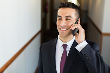 Image showing smiling businessman calling on smartphone at hotel