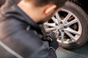 Image showing auto mechanic with screwdriver changing car tire