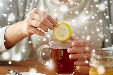 Image showing close up of woman adding lemon to tea with honey