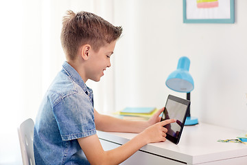 Image showing smiling boy with tablet pc sitting at home desk