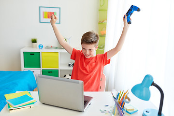 Image showing boy with gamepad playing video game on laptop