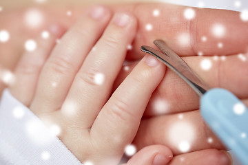 Image showing close up of hand with scissors trimming baby nails