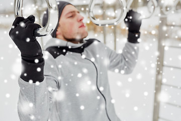 Image showing young man exercising on horizontal bar in winter