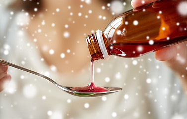 Image showing woman pouring medication from bottle to spoon