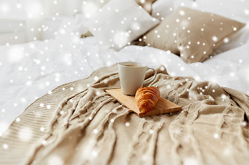 Image showing coffee cup and croissant on plaid in bed at home