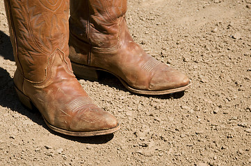 Image showing Two dirty western cowboy boots standing on dirt ground