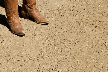 Image showing Two dirty western cowboy boots standing on dirt ground