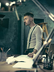 Image showing Portrait of a bearded businessman who is checking details of his upcoming meeting in his notebook and typing.