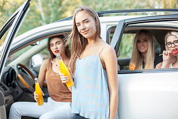 Image showing The young women in the car smiling and drinking juice