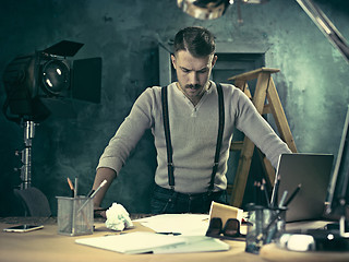 Image showing Portrait of a bearded businessman who is checking details of his upcoming meeting in his notebook and typing.