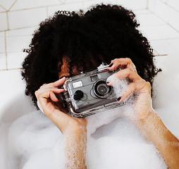 Image showing young afro-american teen girl laying in bath with foam, wearing 