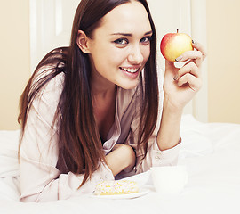 Image showing young pretty brunette woman laying in bed, luxury white interior