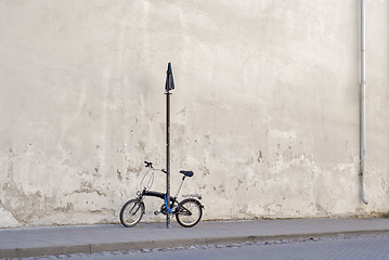 Image showing Bicycle locked to the sign pole near the concrete wall