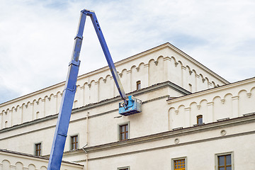 Image showing construction worker fixing house facade using lifting boom machinery
