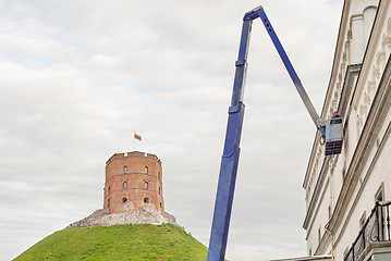 Image showing Gediminas tower on green hill, construction worker fixing house facade