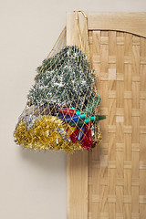 Image showing Mesh bag full of tinsel, lights hanging on the wooden door