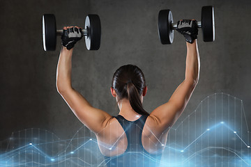 Image showing young woman flexing muscles with dumbbells in gym