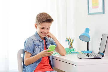 Image showing happy boy with smartphone and laptop at home