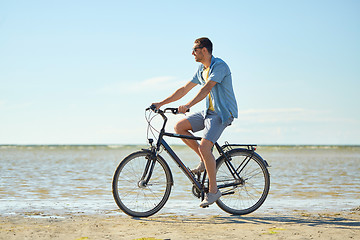 Image showing happy man riding bicycle along summer beach