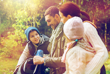 Image showing happy family with backpacks and thermos at camp