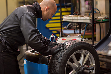 Image showing auto mechanic balancing car wheel at workshop