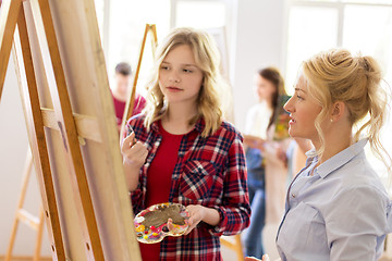 Image showing artists discussing painting on easel at art school