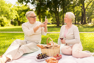 Image showing senior couple taking picture by smartphone at park