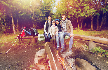 Image showing happy family sitting on bench at camp fire