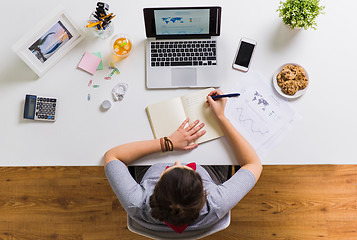 Image showing woman with laptop writing to notebook at office