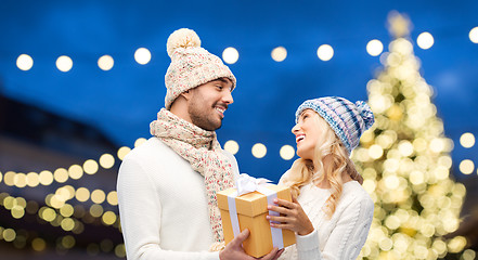 Image showing happy couple with gift box over christmas lights