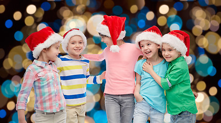 Image showing happy little children in santa hats hugging