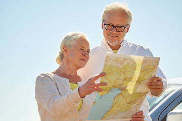 Image showing senior couple at car looking for location on map