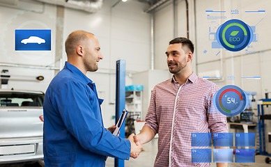 Image showing auto mechanic and man shaking hands at car shop