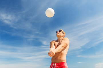 Image showing young man with ball playing volleyball on beach