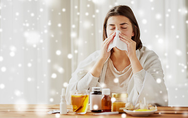 Image showing sick woman with medicine blowing nose to wipe