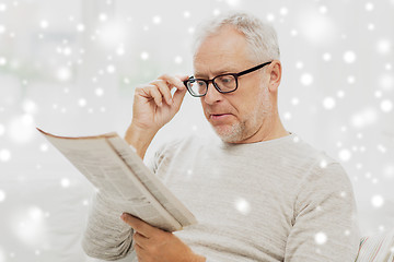 Image showing senior man in glasses reading newspaper over snow