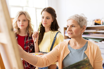 Image showing women with easel and palettes at art school