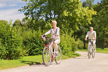 Image showing happy senior couple riding bicycles at summer park