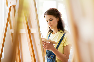 Image showing student girl with easel painting at art school