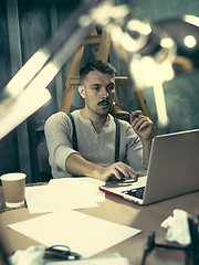 Image showing Portrait of a bearded businessman who is checking details of his upcoming meeting in his notebook and typing.