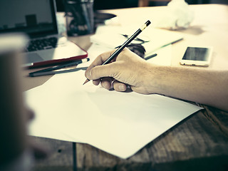 Image showing Vintage hipster wooden desktop side view, male hands with cup and holding a pencil