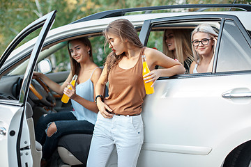 Image showing The young women in the car smiling and drinking juice