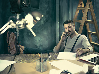 Image showing Portrait of a bearded businessman who is working with his notebook at loft studio.